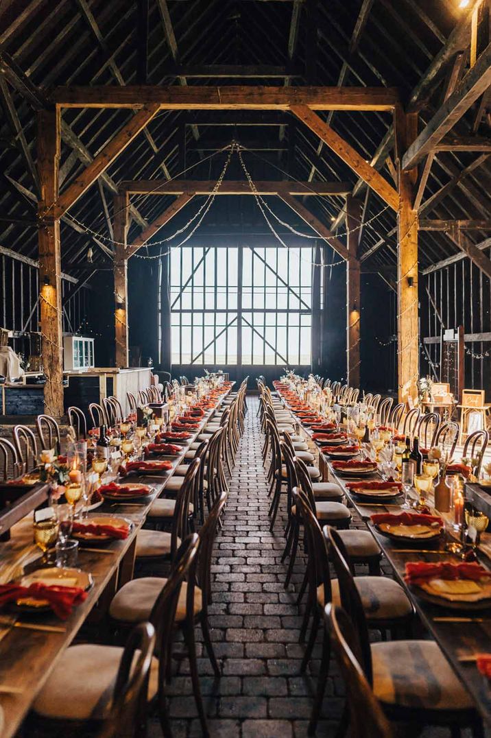 Classic rustic wedding tablescapes with rose centrepieces in reception room of Elmley Nature Reserve wedding venue with exposed beams and large window 