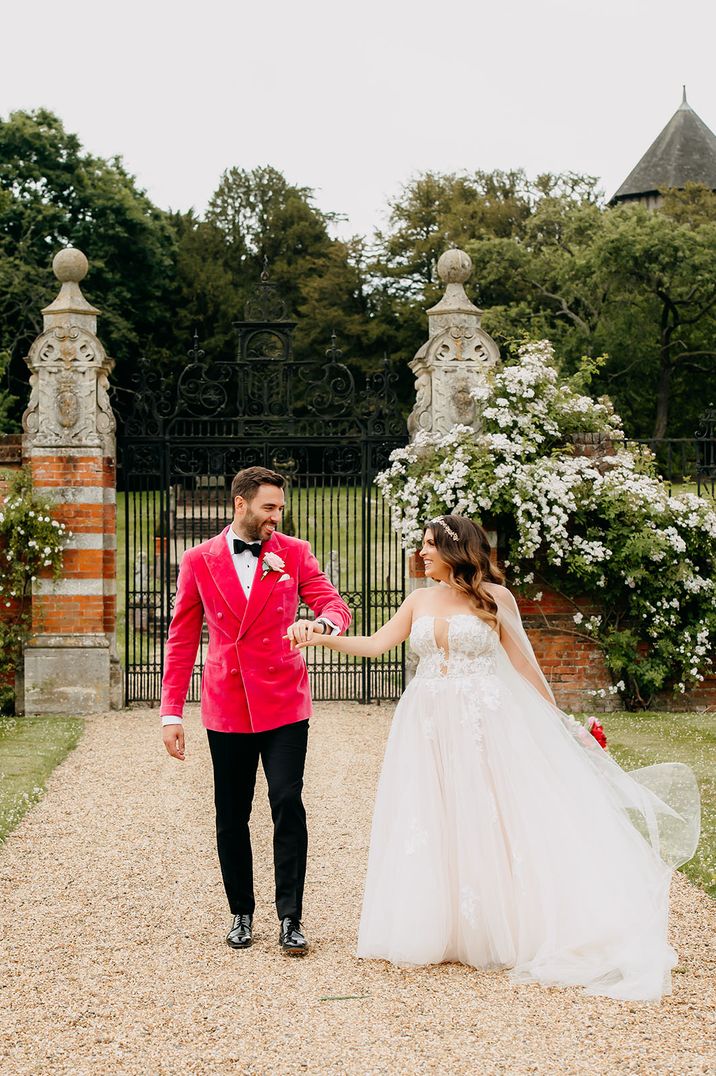 Groom in hot pink velvet double-breasted suit jacket walking with the bride 