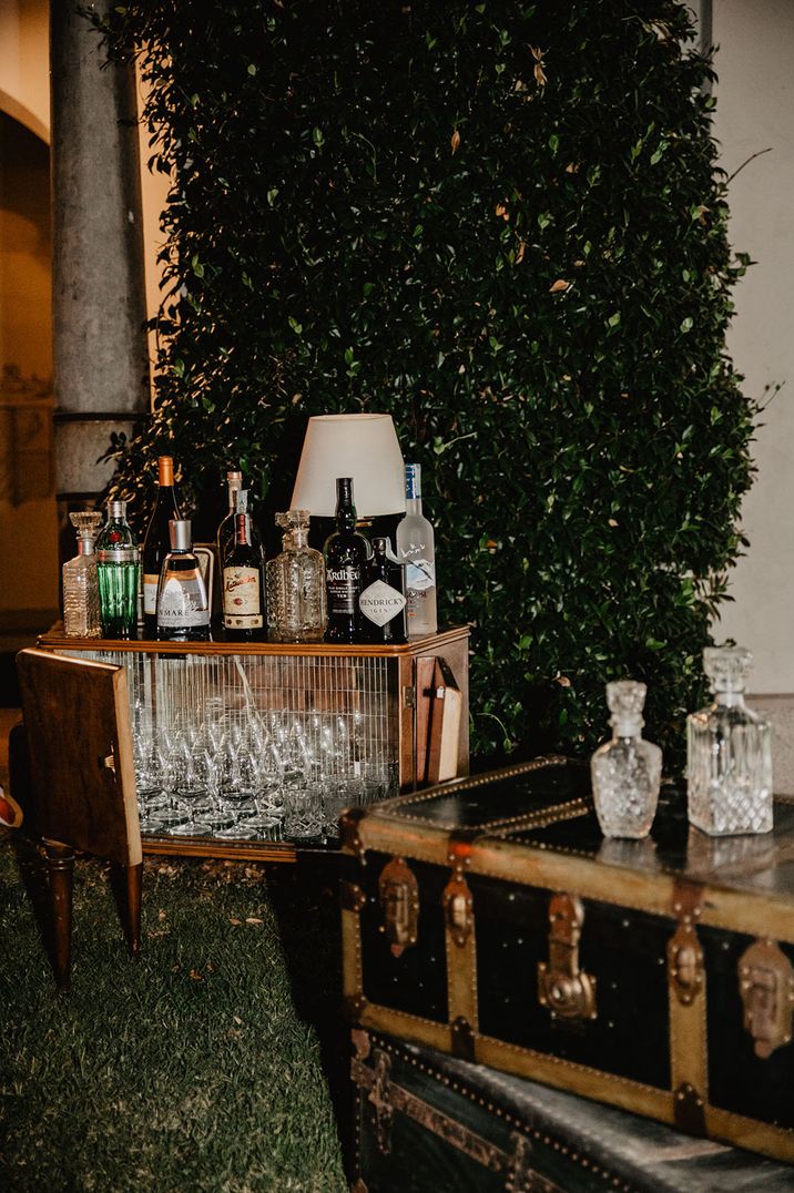 Unique cocktail cart with cart filled with empty glasses and spirits for guests with crystal decanters 