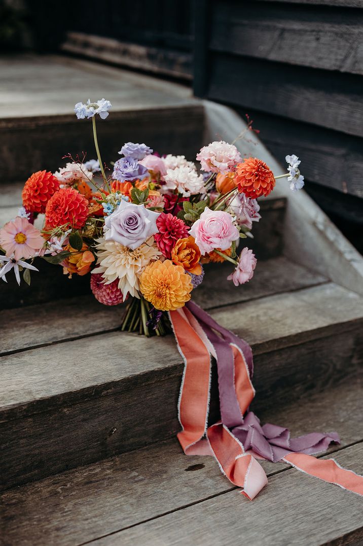 Colourful wedding bouquet with carnations, roses and dahlias tied with ribbon 