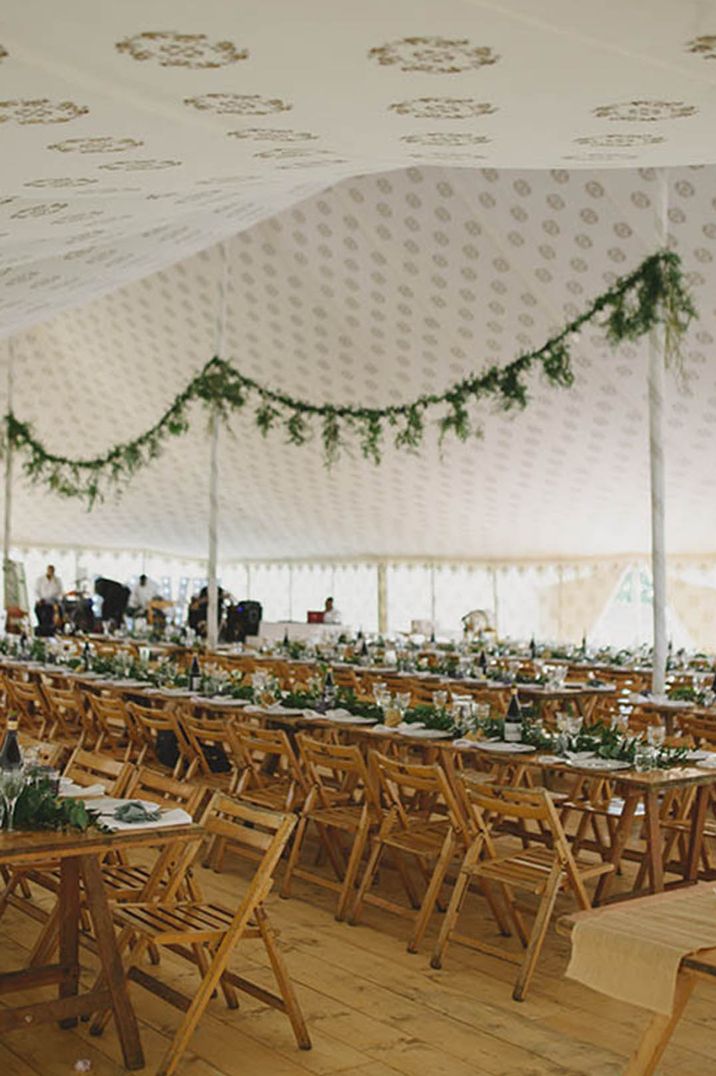 Marquee wedding at Pencarrow with hanging foliage decor over long banquet tables 