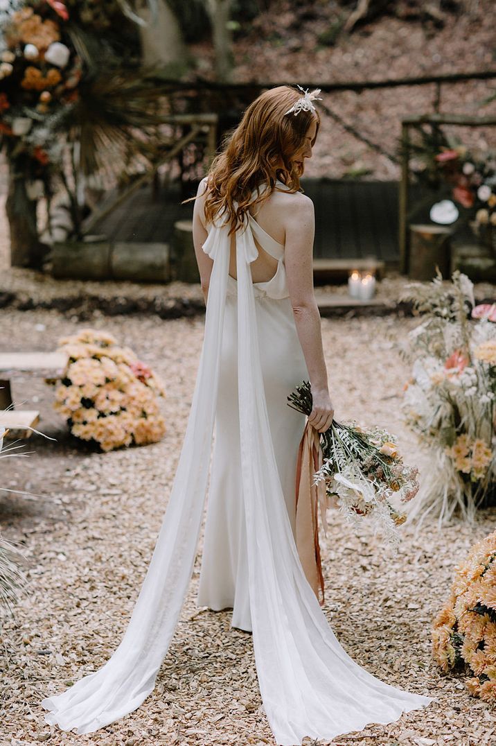 Bride in a romantic wedding dress with long wedding bow tied at the back sweeping the floor 