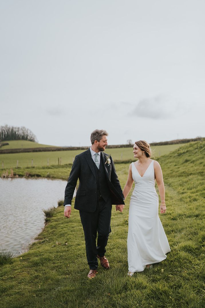 Bride wearing plunging wedding dress with v-neckline walking with the groom 