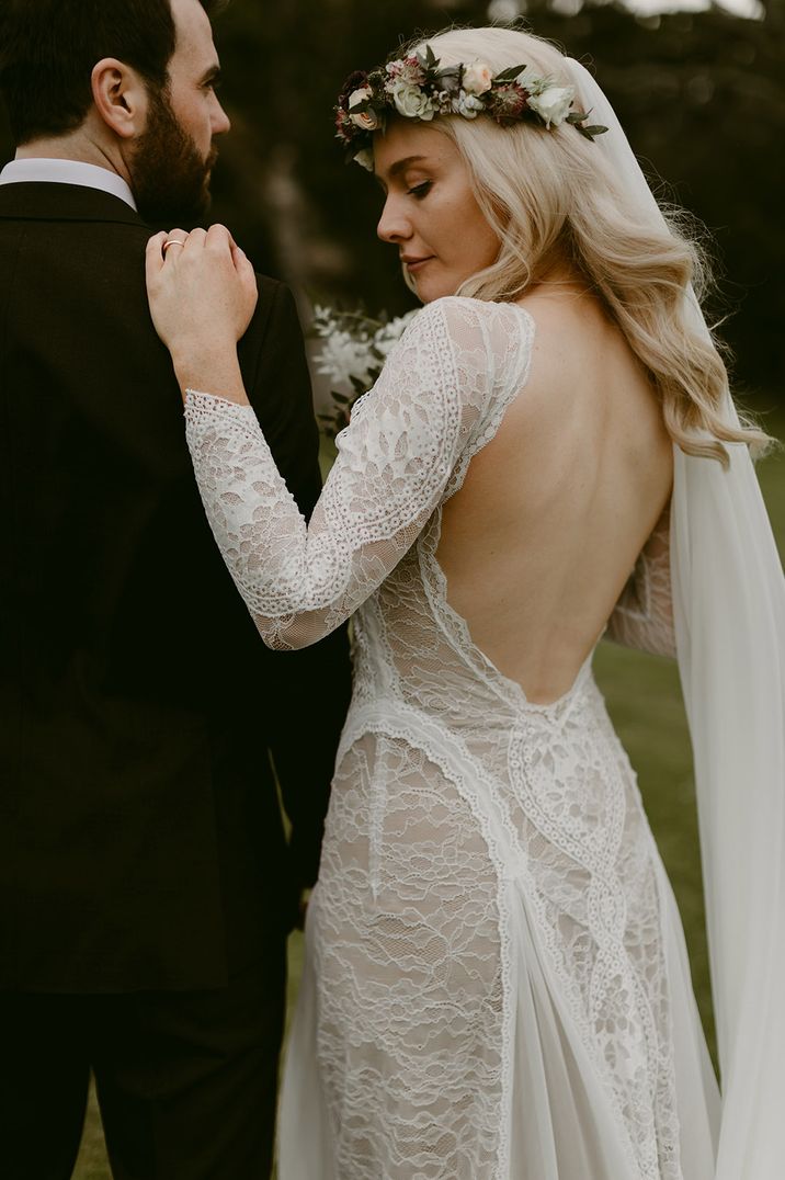 Bride in low back long sleeve lace wedding dress with groom 