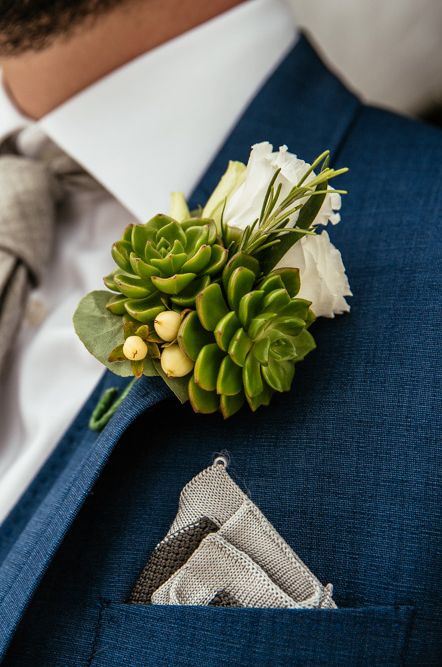 Groom in a navy suit with white rose and succulent buttonhole 