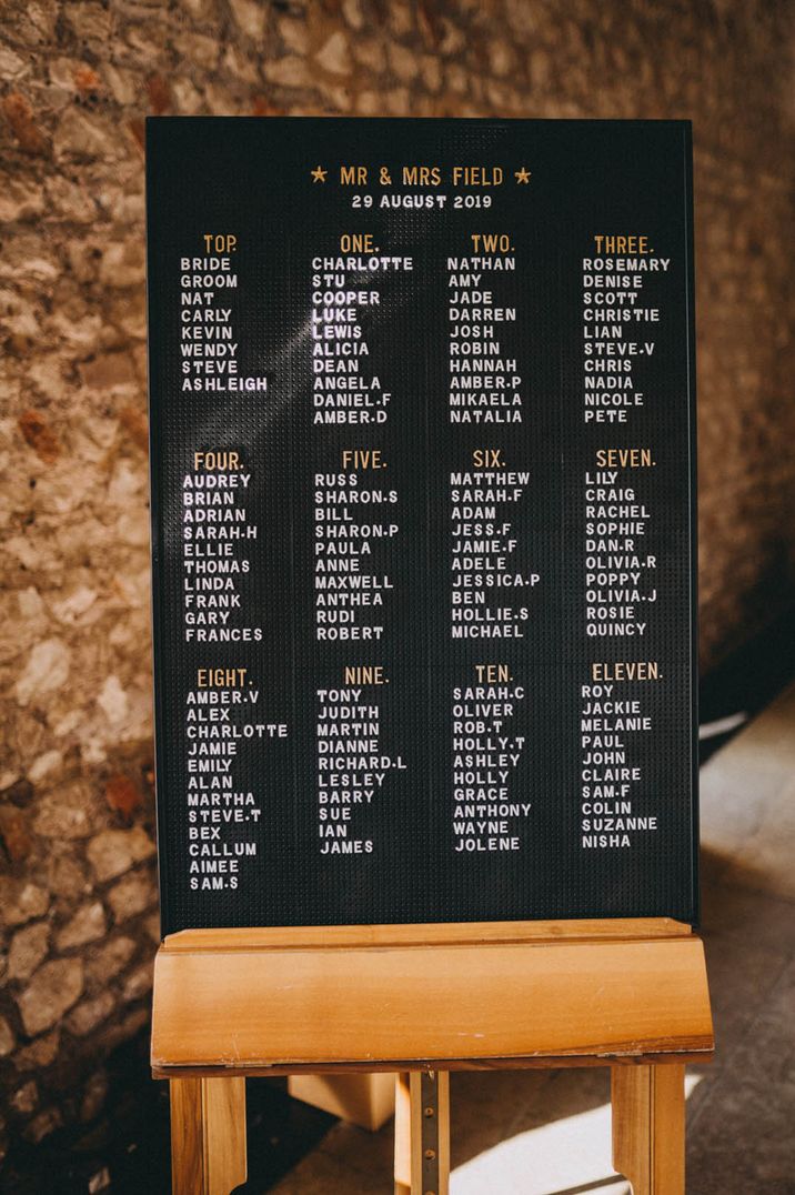 Black peg board seating chart on a wooden easel 