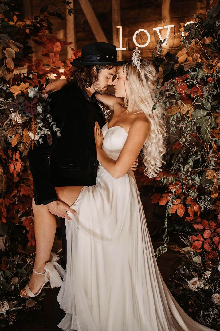 Bride in corset style strapless wedding dress with headband with the groom in a black suit and hat for the Halloween theme wedding 