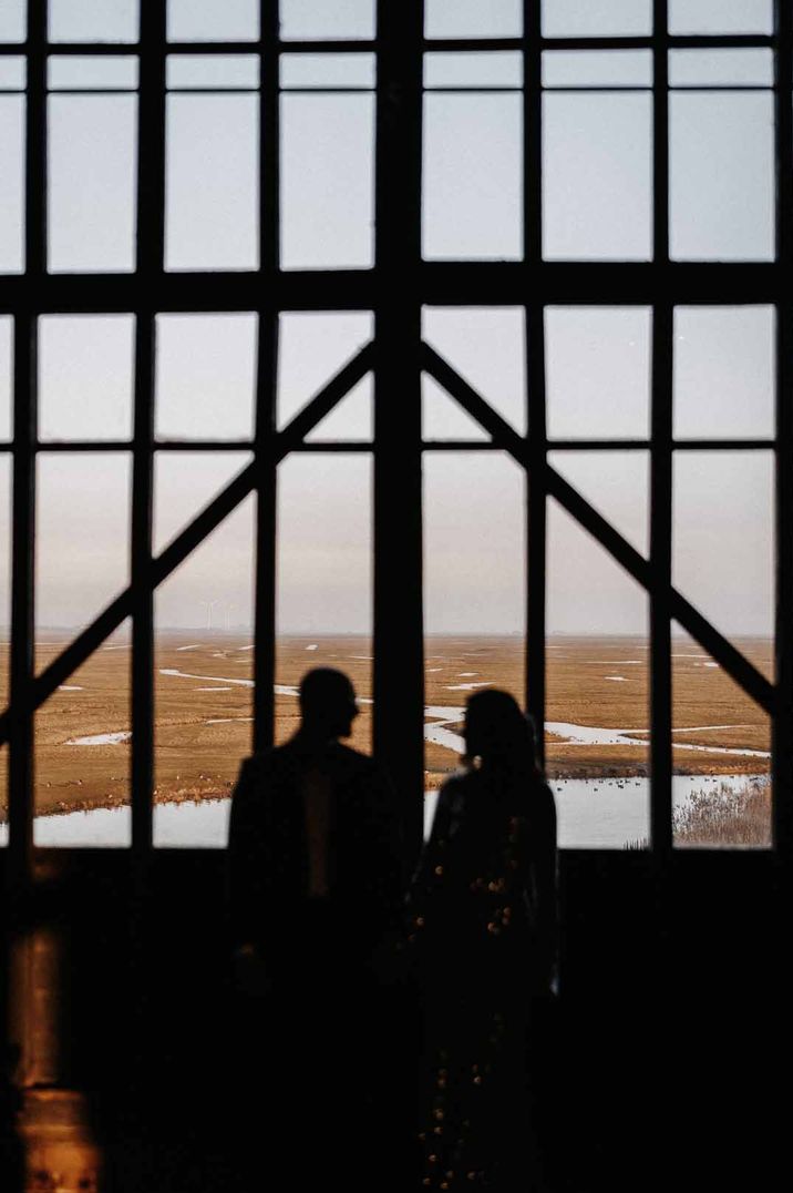 Bride and groom looking out at Elmley Nature Reserve land - one of the most Instagrammable wedding venues 