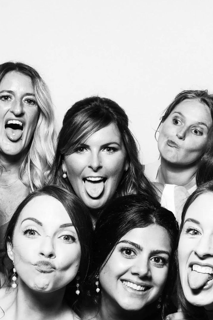 Black and white image of a group of women smiling and posing in a photo booth style image by Studio Rouge Photography