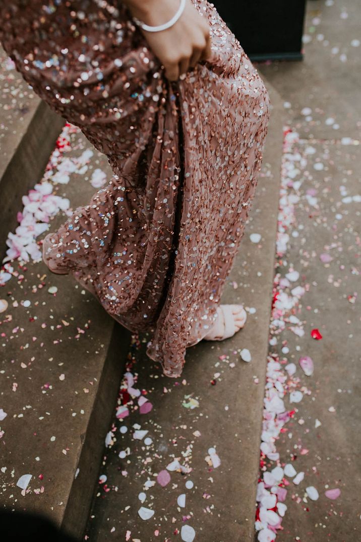 Bride wears pink sequin wedding dress whilst walking across colourful confetti 