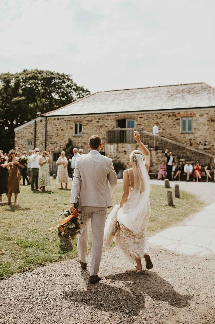 Bride and groom walking and dancing towards guests at Nancarrow Farm Cornwall wedding venue 