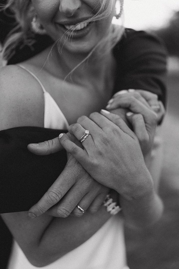 Bride being embraced by groom wearing a small round brilliant diamond ring