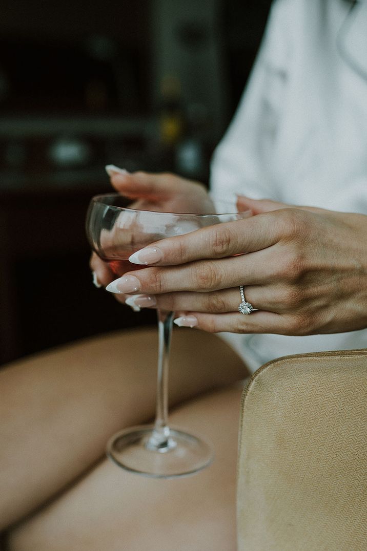 Round brilliant halo engagement ring worn by bride with stiletto pearl nails 