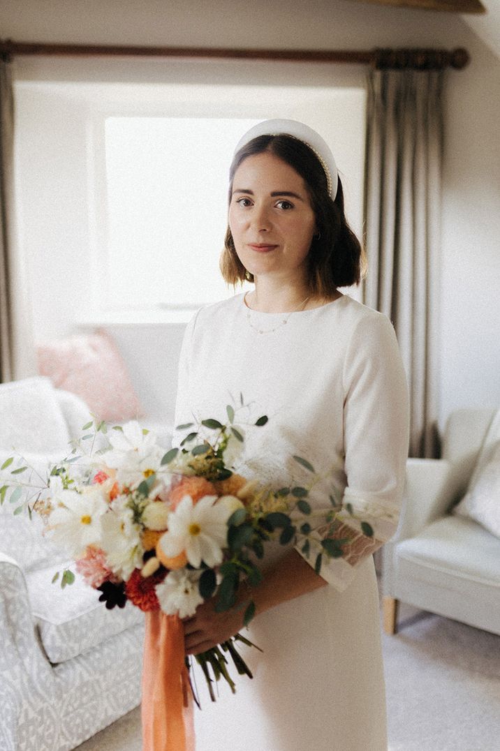 Bride wearing headband accessory holding bouquet with cosmos flowers 