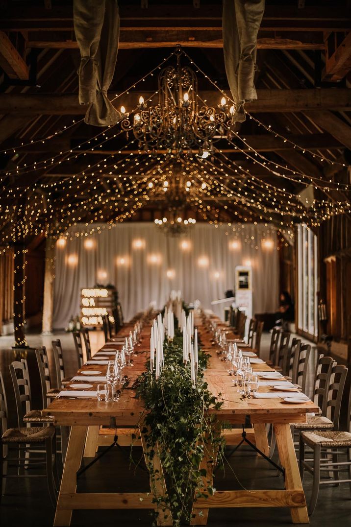 intimate wedding reception with fairy lights, foliage table runner and white taper candles table decor