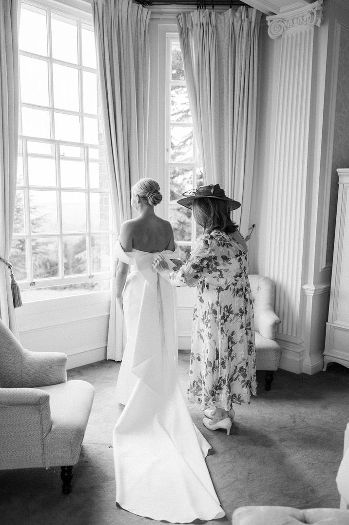 Mother of the bride helps the bride get into her wedding dress for the big day 