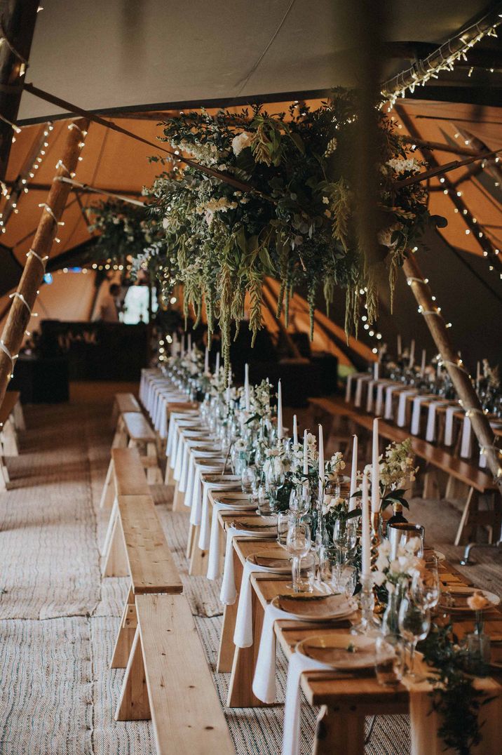 Tipi wedding reception with white taper candles and green and white wedding flowers 