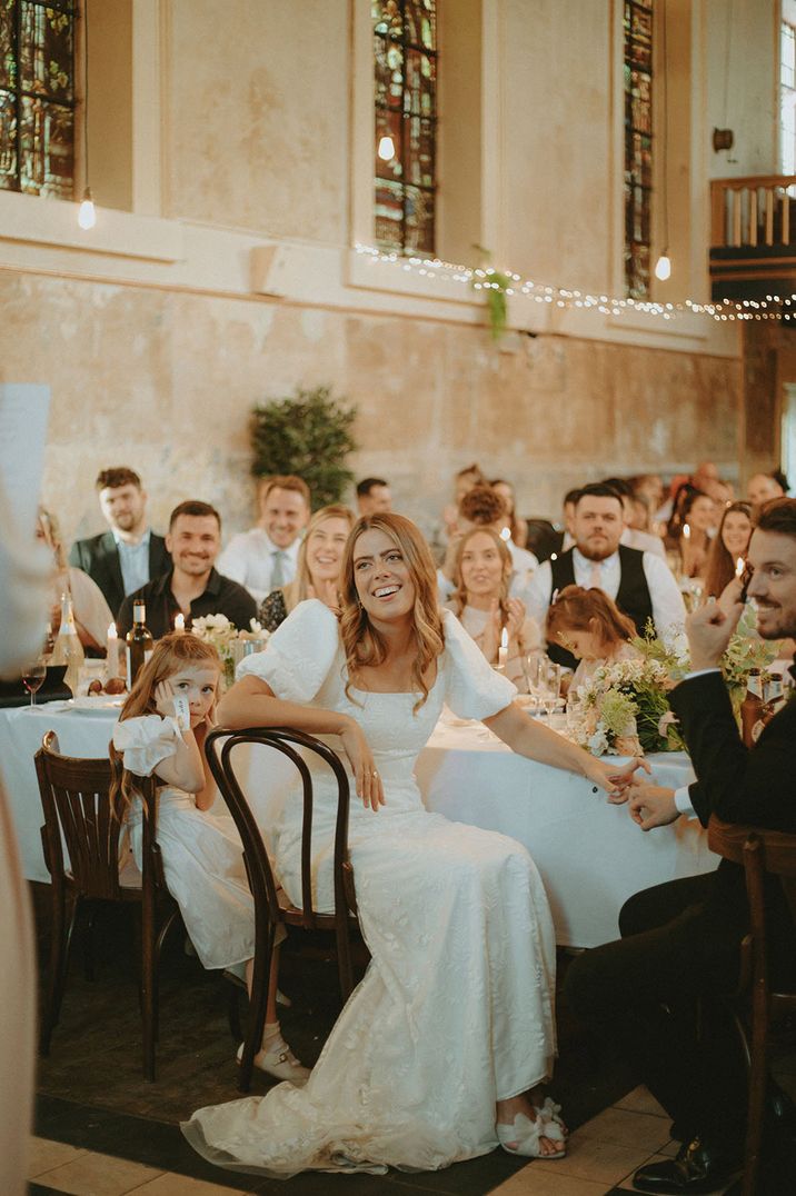 Bride in square neck and puff sleeve wedding dress listening to the maid of honour speech