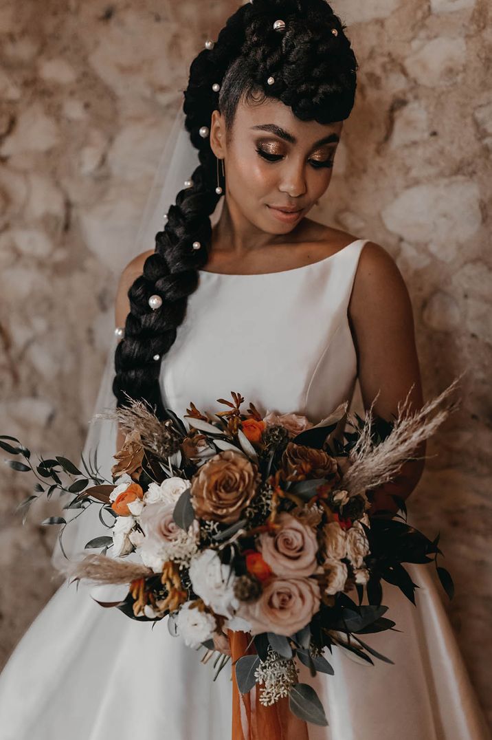 Bride in halterneck satin wedding dress with large pearl hair accessories 