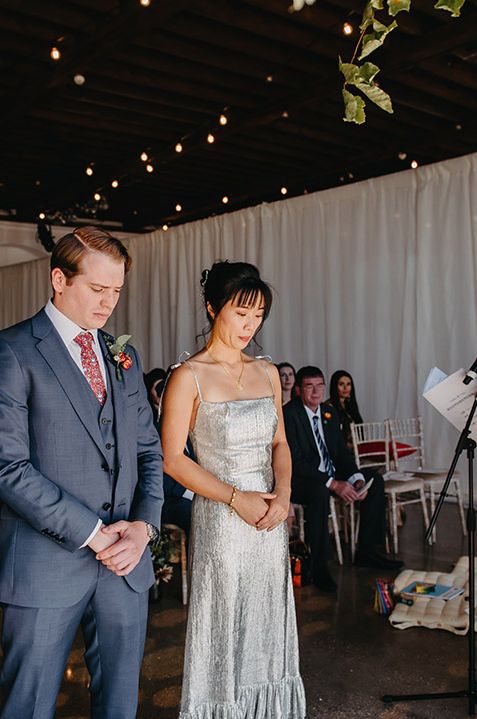 Bride in sparkly The Vampire's Wife wedding dress standing with groom in blue suit for London wedding ceremony 