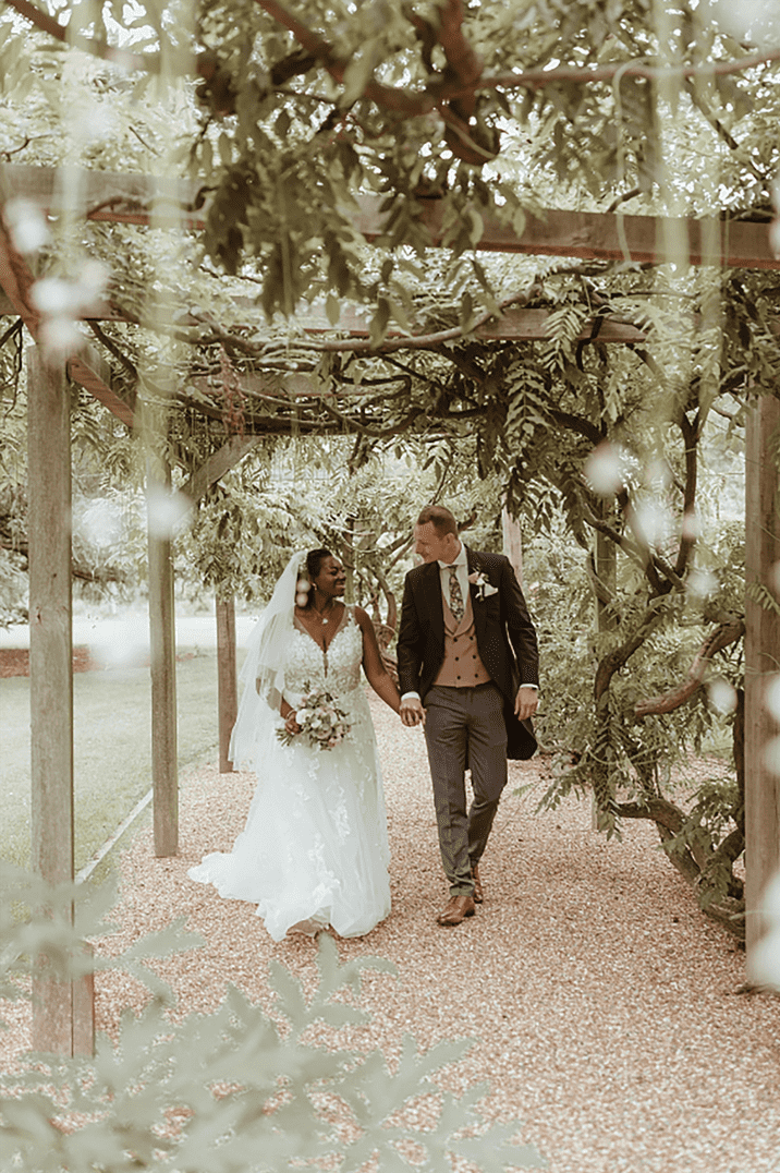 Bride in floral patterned wedding dress with groom in three piece pink morning suits at wedding 