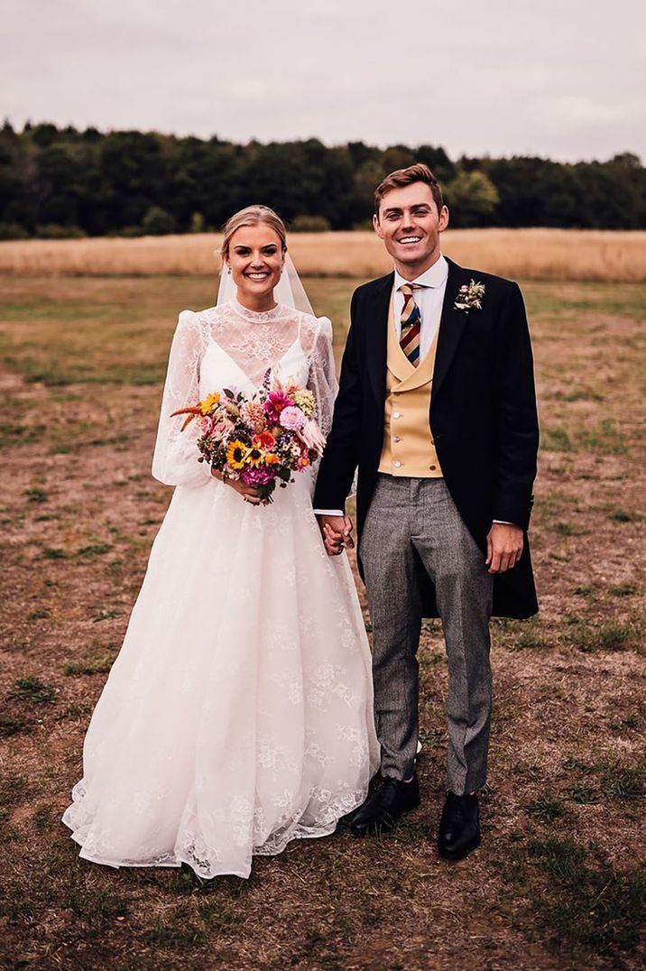 Groom wearing a morning suit with a yellow waistcoat with the bride in lace wedding dress 