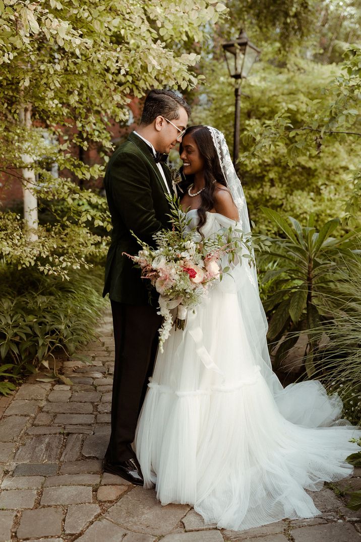 Bride wearing embroidered cathedral length veil with the groom in a green velvet suit for wedding vow renewal 