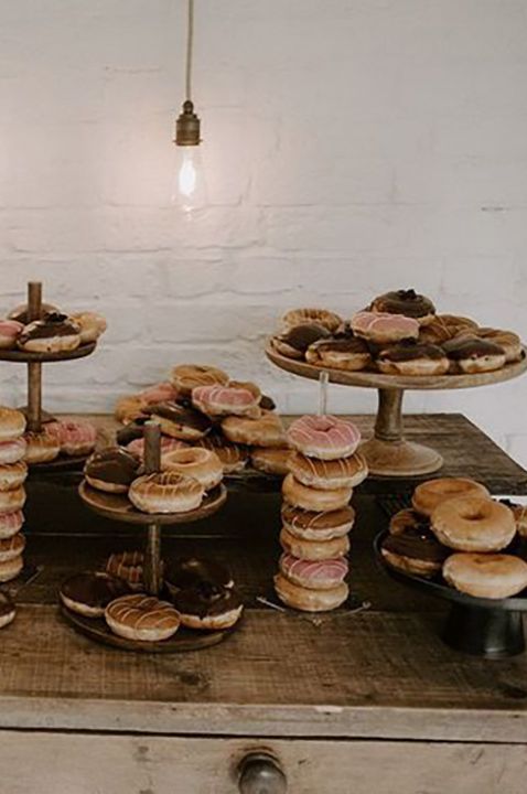 Dreamy dessert table with towers and plates of doughnuts in different flavours with coloured icing 