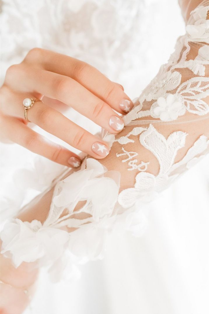 Bride with white nail art wearing a pearl engagement ring 