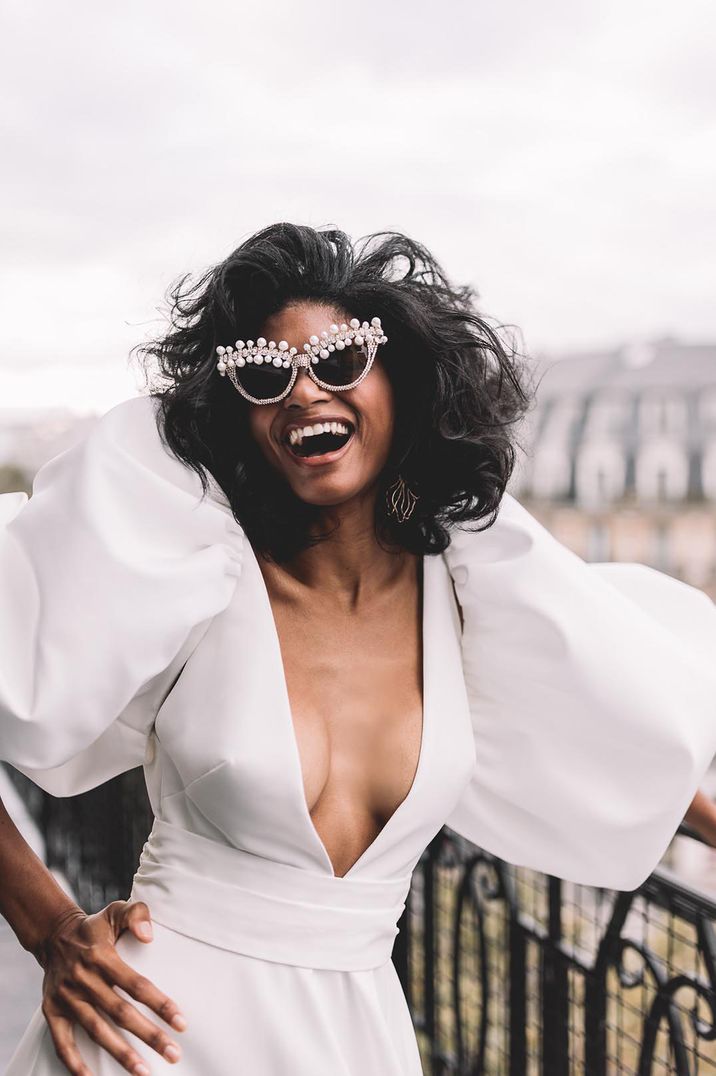 Bride wears pearl embellished heart shaped sunglasses and V-neck wedding dress