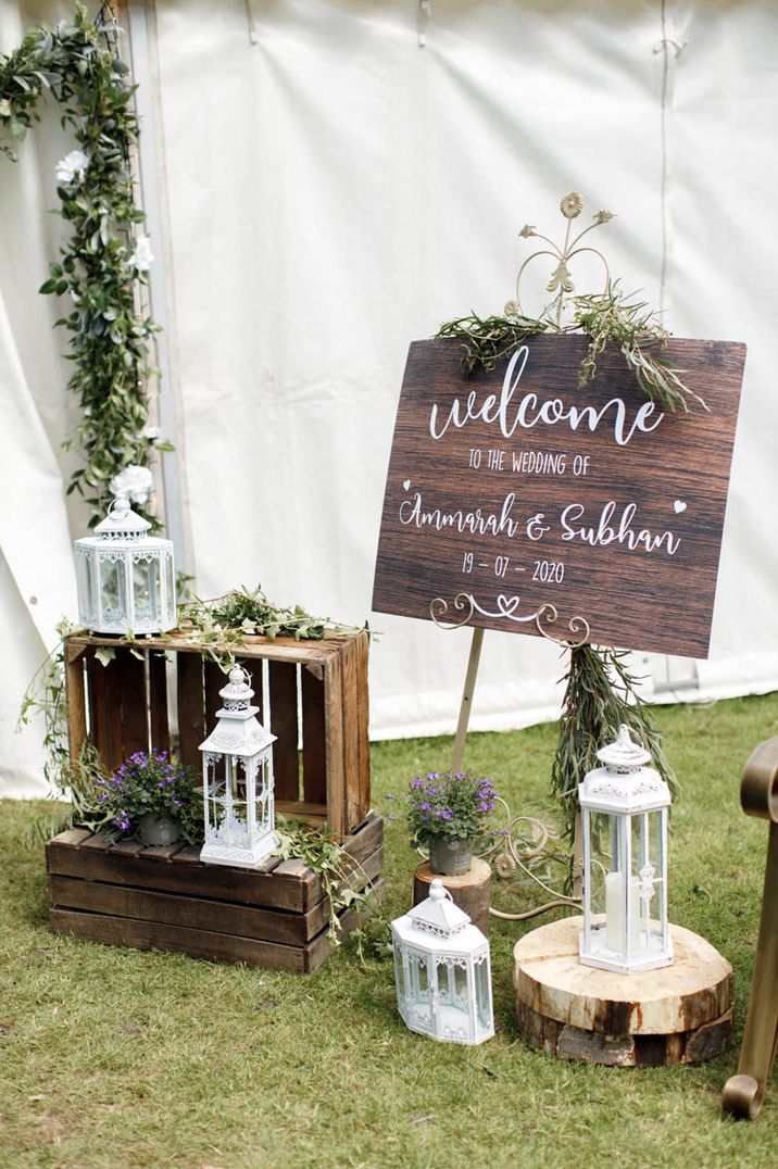 Rustic wooden wedding welcome sign with white lanterns and wooden crates for wedding signage 