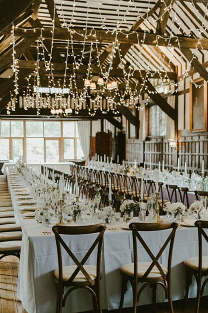 Rustic oak beam Ramster Hall wedding venue decorated with fairy lights with white wedding tables 