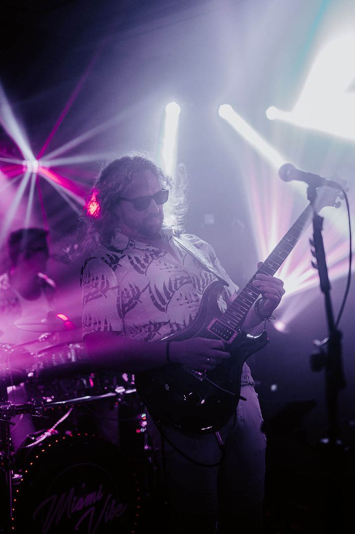 Guitarist in funky shirt playing live music at party 