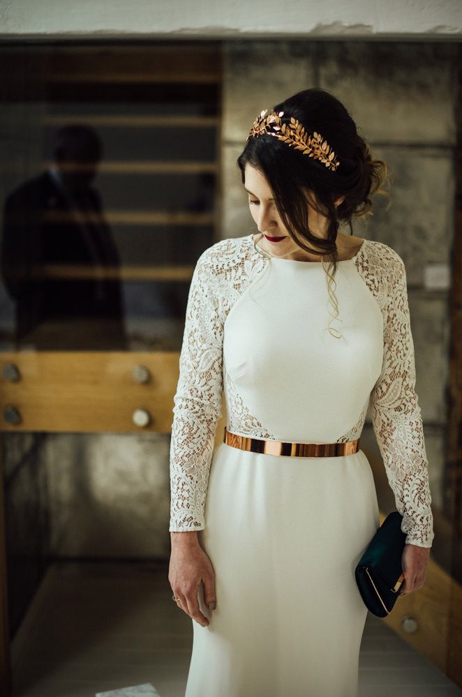 Bride in a fitted wedding dress with high neck, lace long sleeves and metallic belt