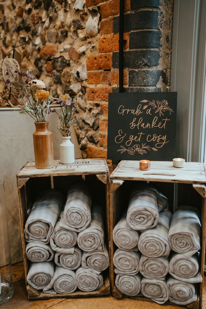 Wooden crates full of grey striped blankets for wedding favours 