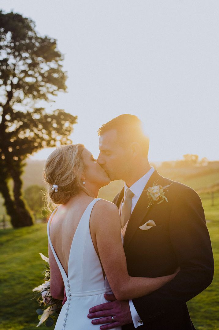 Botley Hill Barn wedding with the bride and groom sharing a kiss together during golden hour 