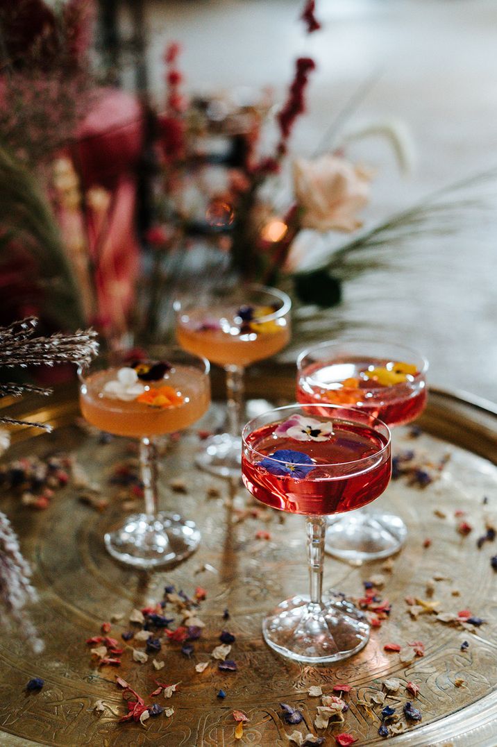 Red and orange wedding cocktails decorated with edible flowers 