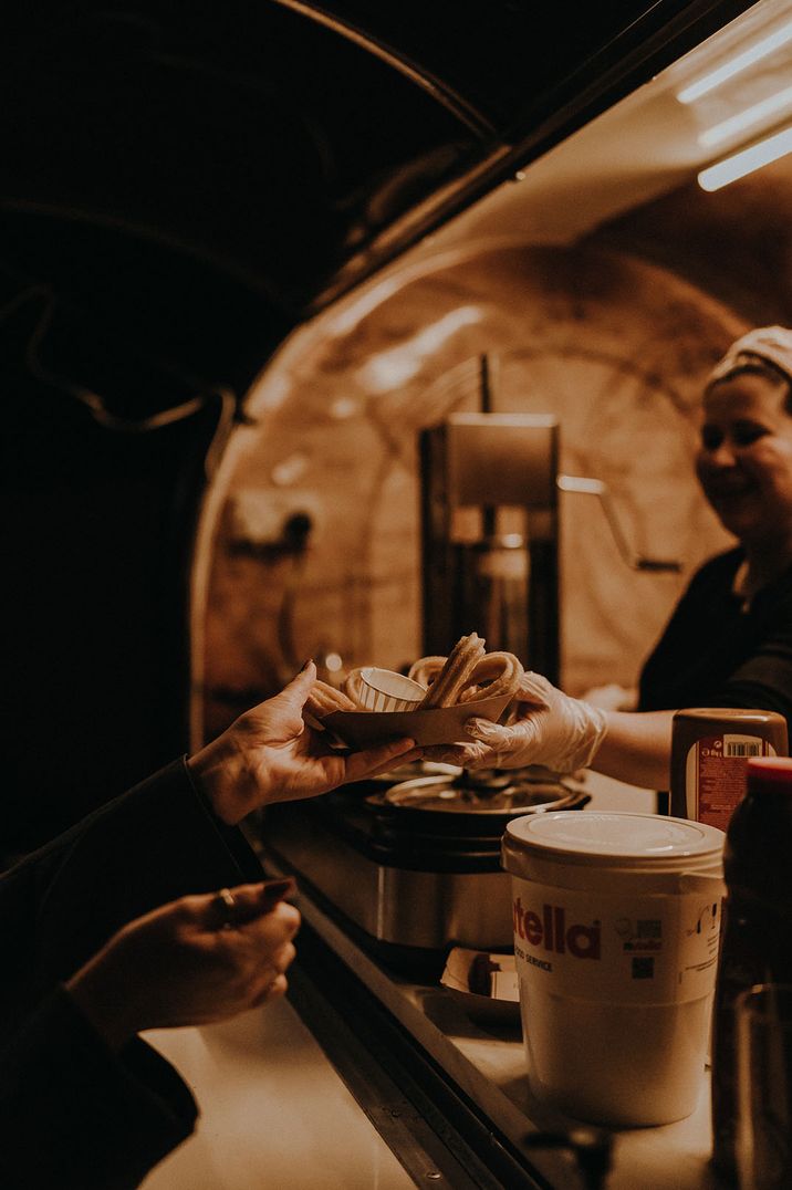 A food stand making churros giving them to guests 