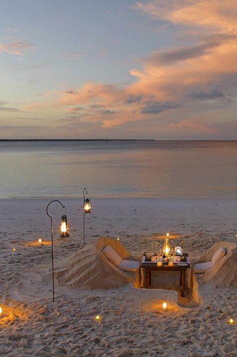 Image of honeymoon destination at Mnemba Island with candlelit table and chairs setup for couple