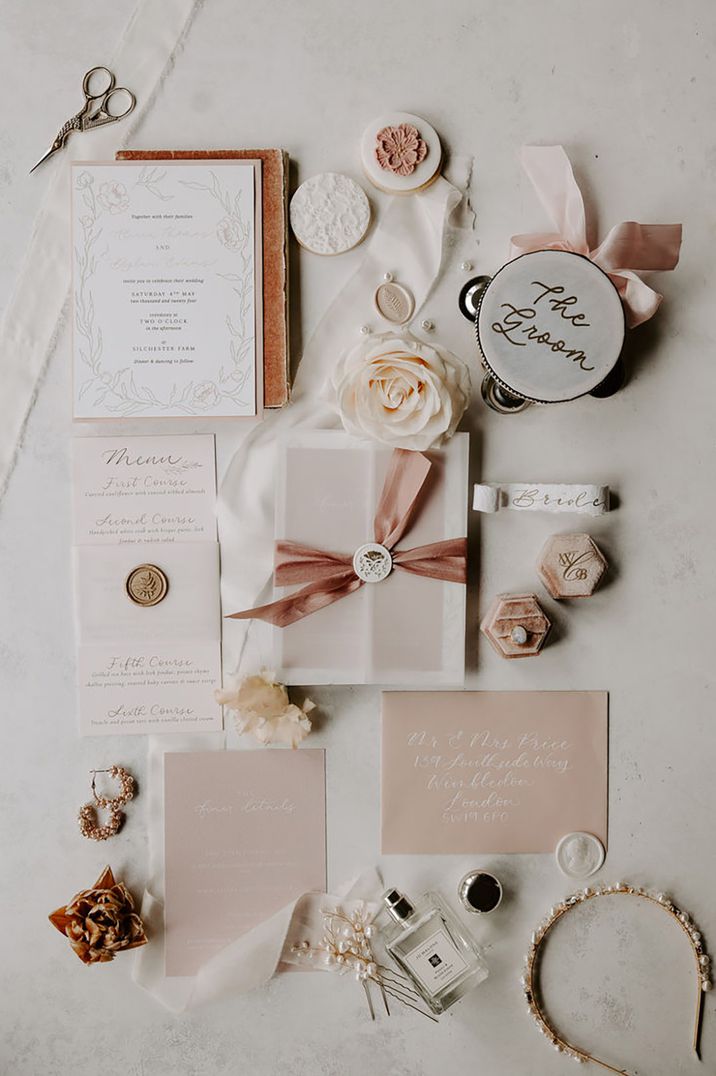 Cream and blush pink wedding invitation suite with pink ribbon, white wax seal with Jo Malone London wedding perfume, and pearl bridal accessories