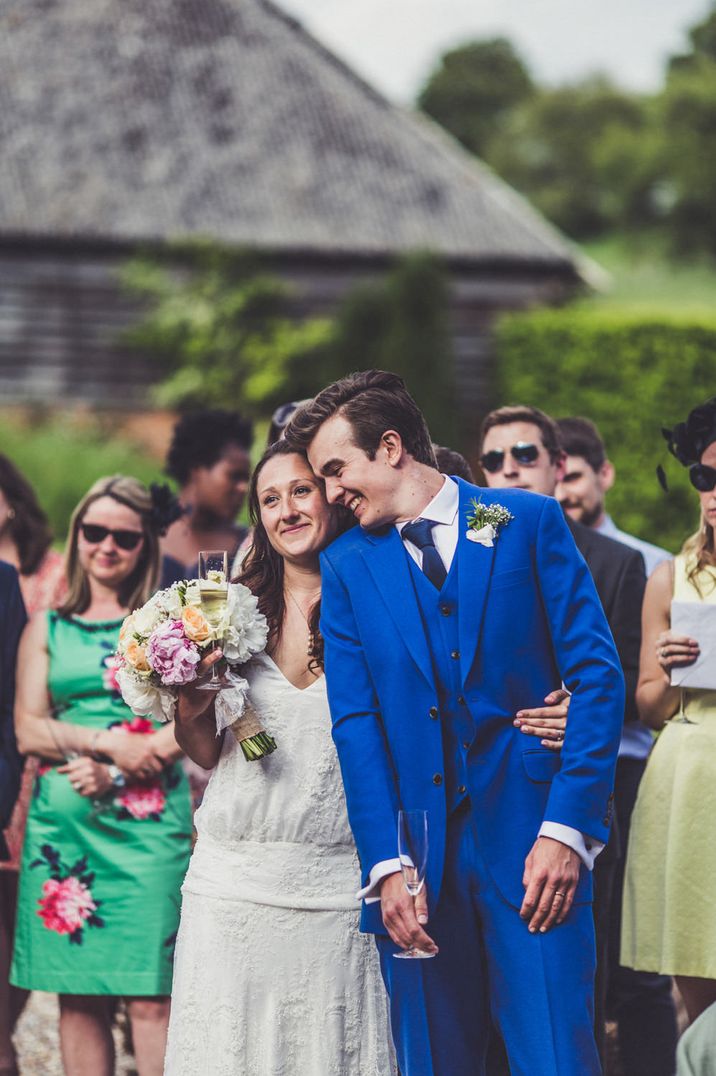 Bride in a Charlie Brear wedding dress embracing her groom in an electric blue suit 