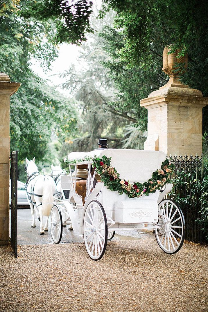 Classic white horse drawn carriage for wedding transport with mixed floral decorations