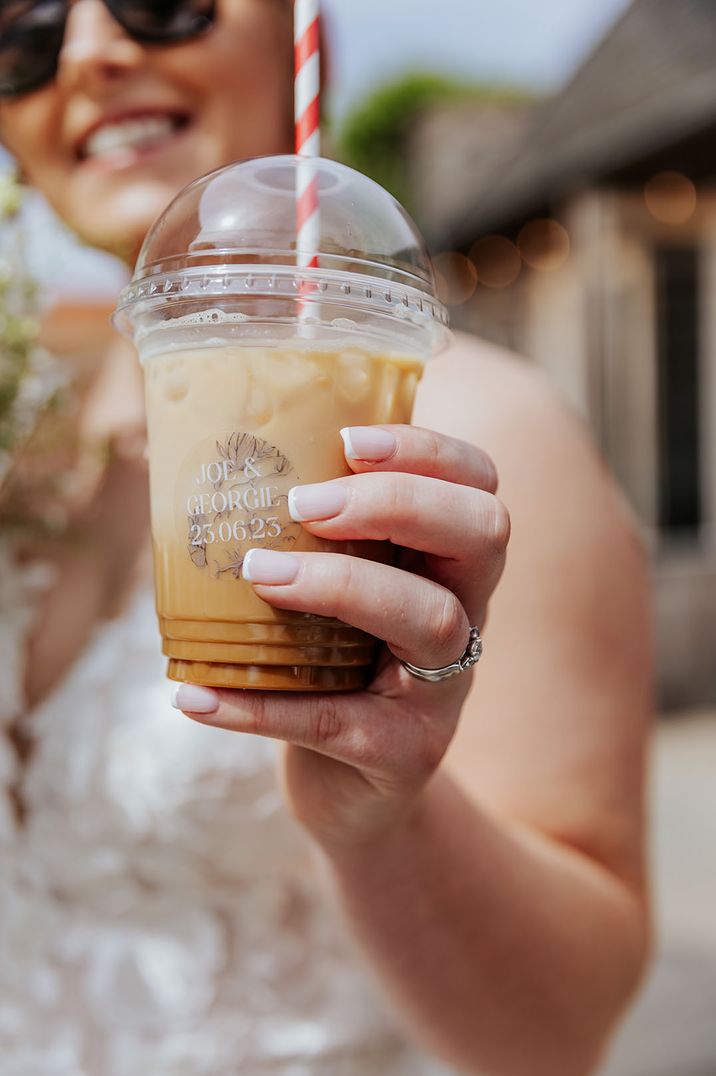 Bride drinking iced coffee in plastic cup with paper straw from the coffee van 