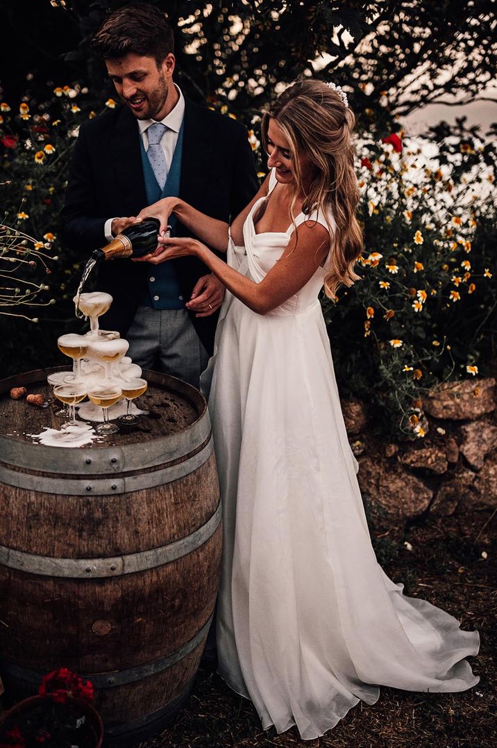 The bride and groom pour champagne into their wedding champagne tower 