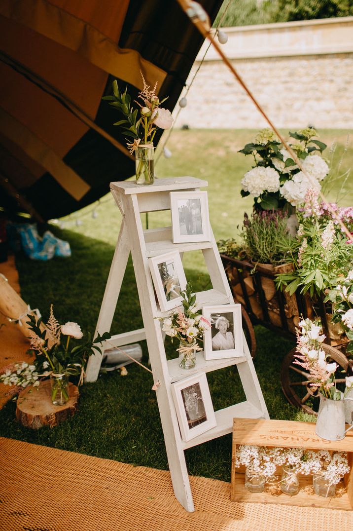 Step ladder rustic wedding decor with photos of family displayed on it 