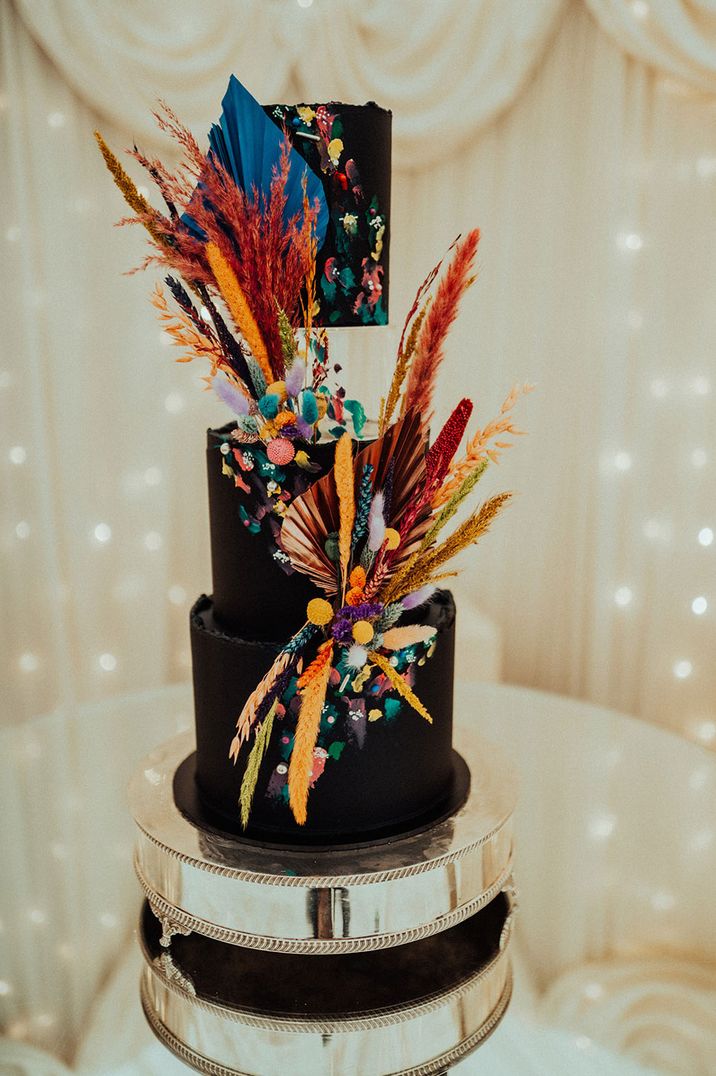 Tall three tier dark wedding cake with bright and colourful dried flower pampas grass decor 