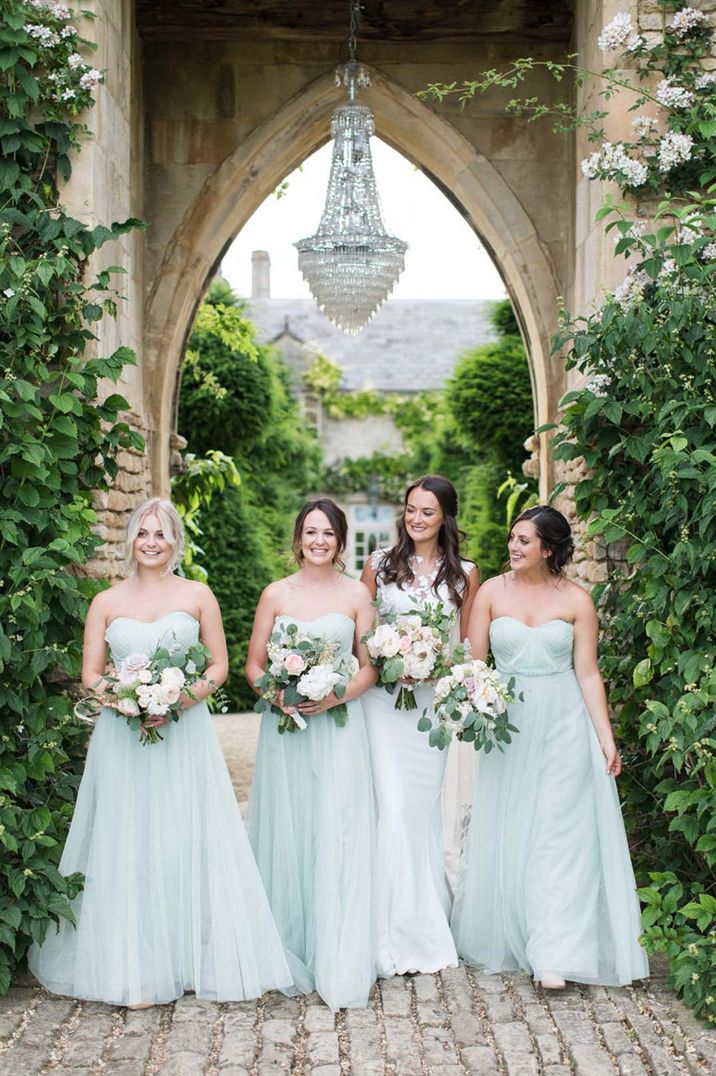 Bridesmaids in strapless sweetheart light green dresses with bride in illusion lace wedding dress 