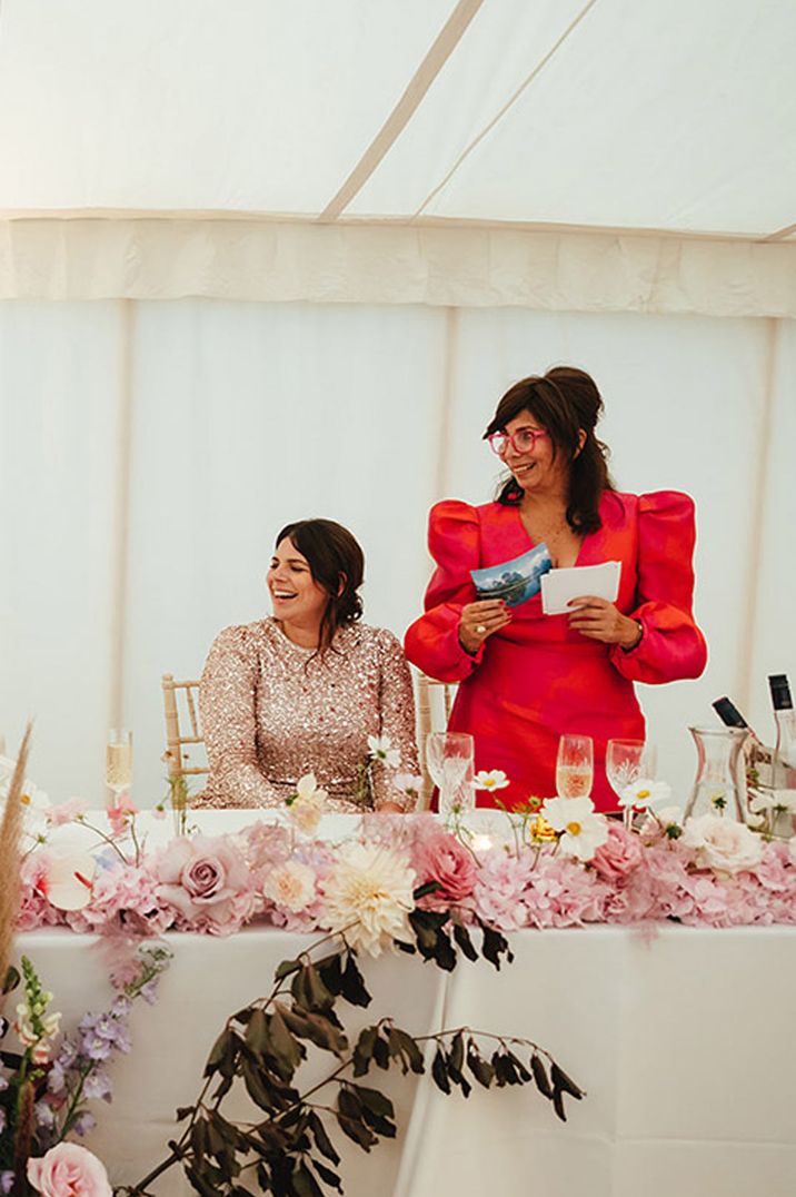 Maid of honour giving speech in red dress with puff shoulders and red glasses