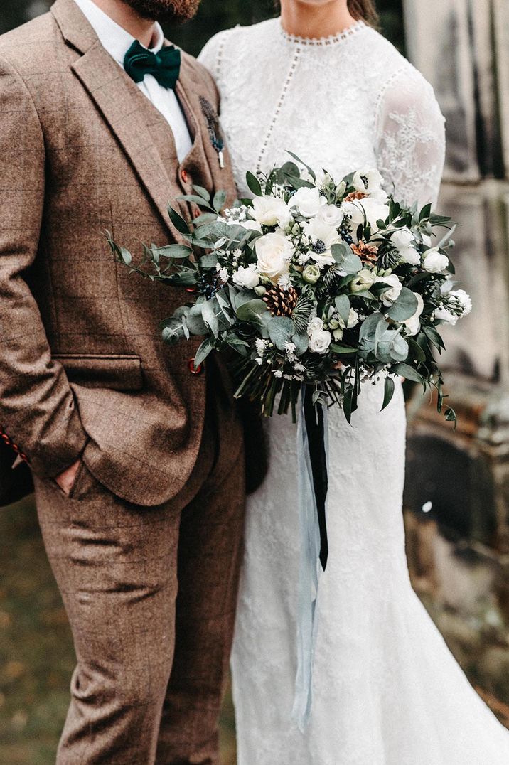 Bride holding a classic white flower wedding bouquet with the groom in a tweed suit 