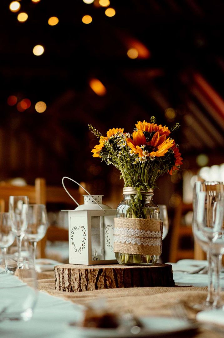 White and neutral wedding tablescape with sunflowers in a mason jar decoration